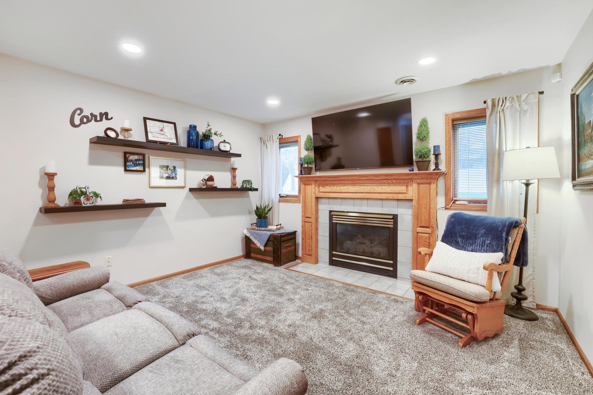 The cozy lower level family room is anchored by the gas fireplace
