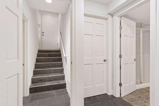 Lower level landing between 3/4 bath, laundry, wet bar, and family room. Door at top of stairs leads to garage.