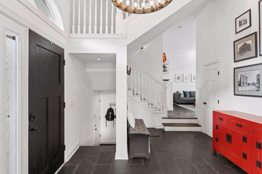 Dramatic two-story entry with elegant staircase, tile flooring, and open views into the main living space