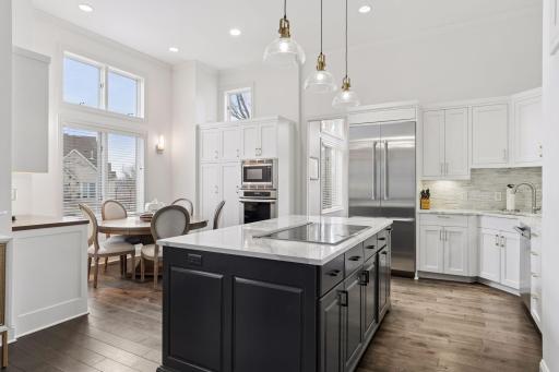 Beautiful chefâs kitchen featuring quartz island, custom cabinetry, stainless appliances, and stylish glass pendant lighting.