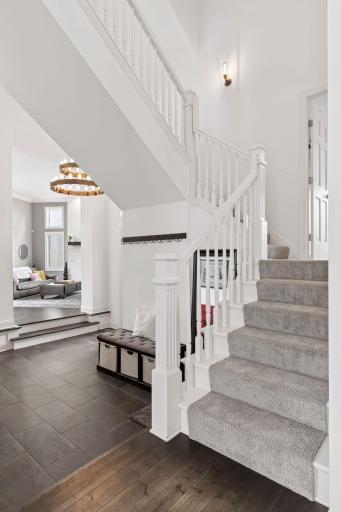 Dramatic two-story entry with elegant staircase, tile flooring, and open views into the main living space