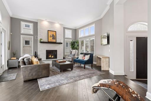Living room with soaring ceilings, oversized windows, and a modern gas fireplace creating a warm focal point.