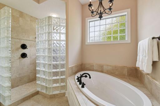 This spa worthy bathroom includes a large walk-in shower with two shower heads and a jetted bathtub.
