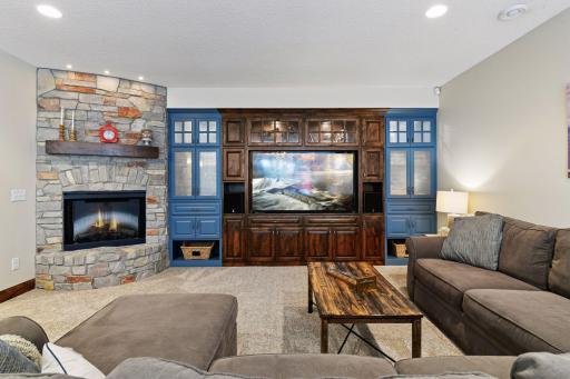 Cheer on your sports team or enjoy movie night curled up in the lower level family room. An electric fireplace anchors a wall of built-in cabinetry and entertainment center.