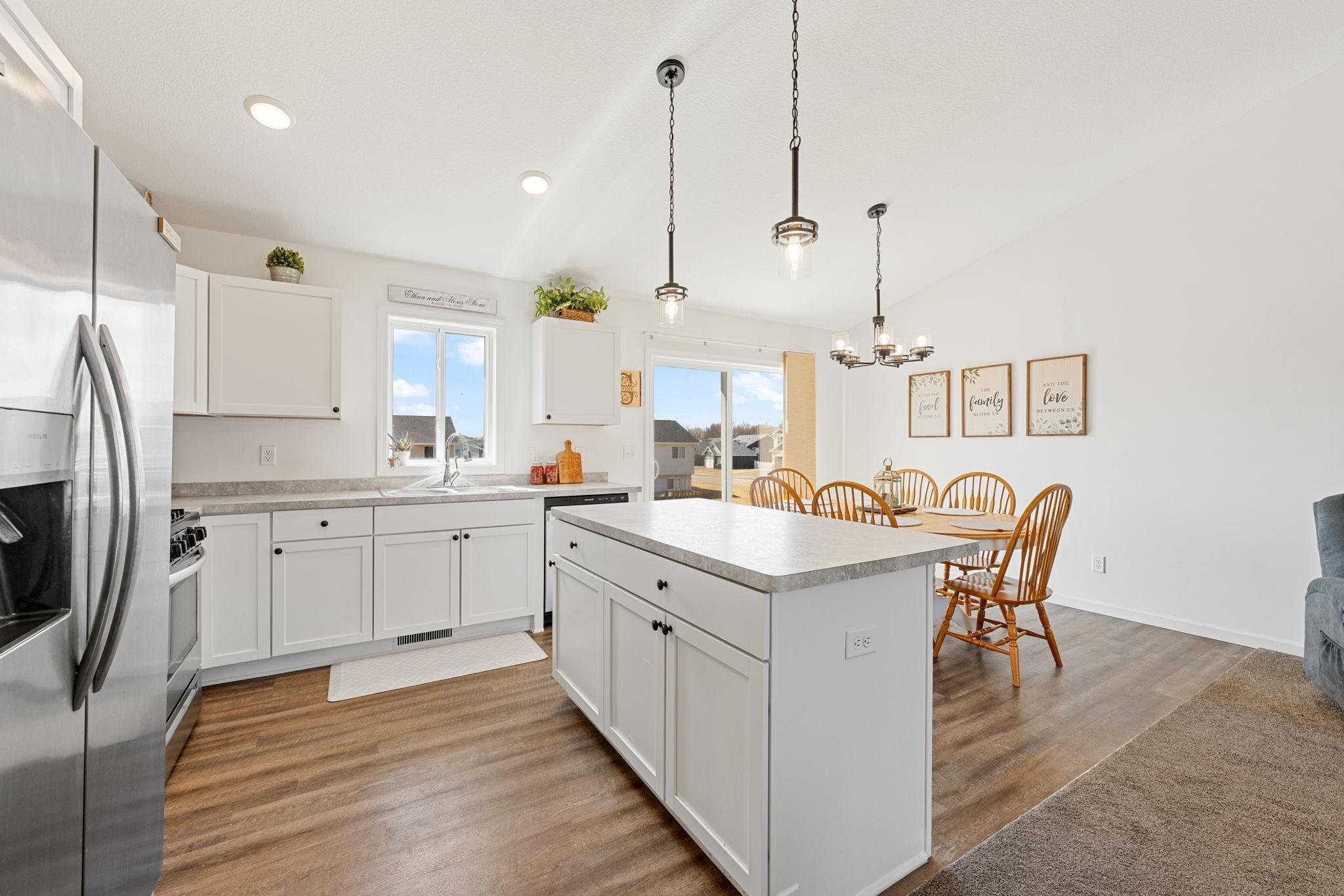 Stylish & functional kitchen with white shaker cabinets & modern black hardware, stainless steel appliances and a large center island