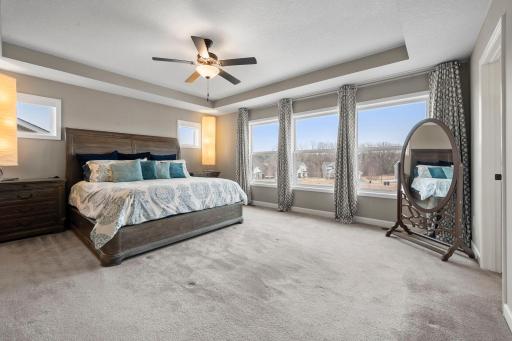 The primary bedroom features a tray ceiling and wall to wall windows overlooking the backyard.