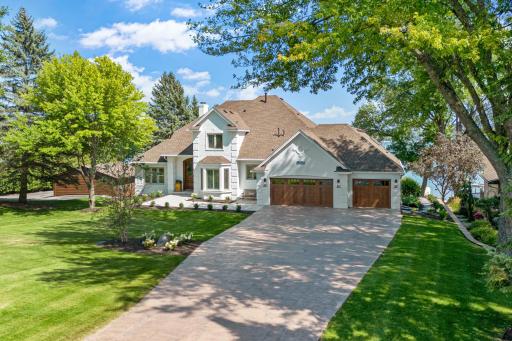 Zoomed out to highlight the spacious front lawn and extended driveway that create a beautiful approach to the property.