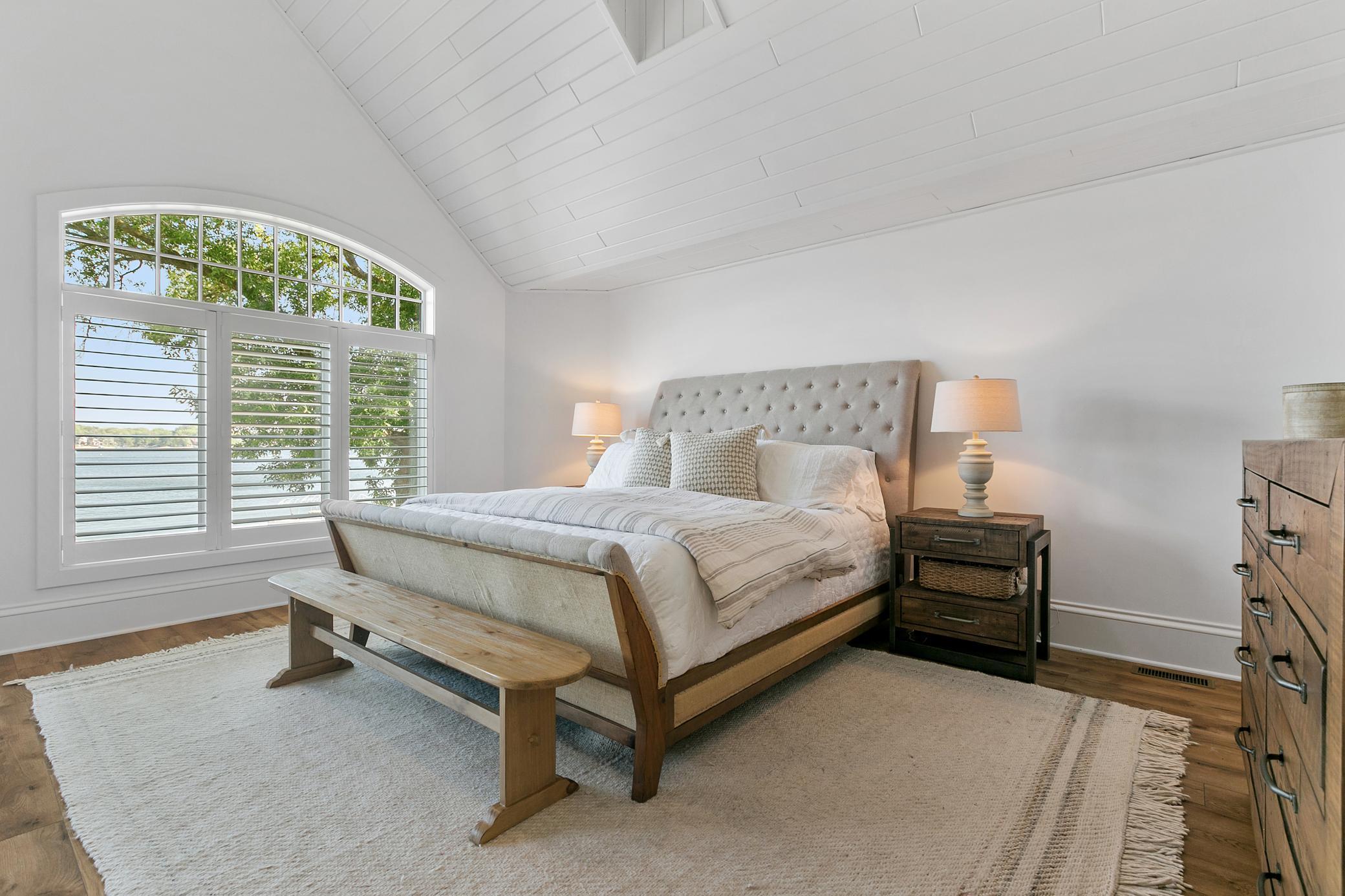 Private main-level primary suite featuring a cozy gas fireplace, elegant wood flooring, and direct walkout access to the deck.