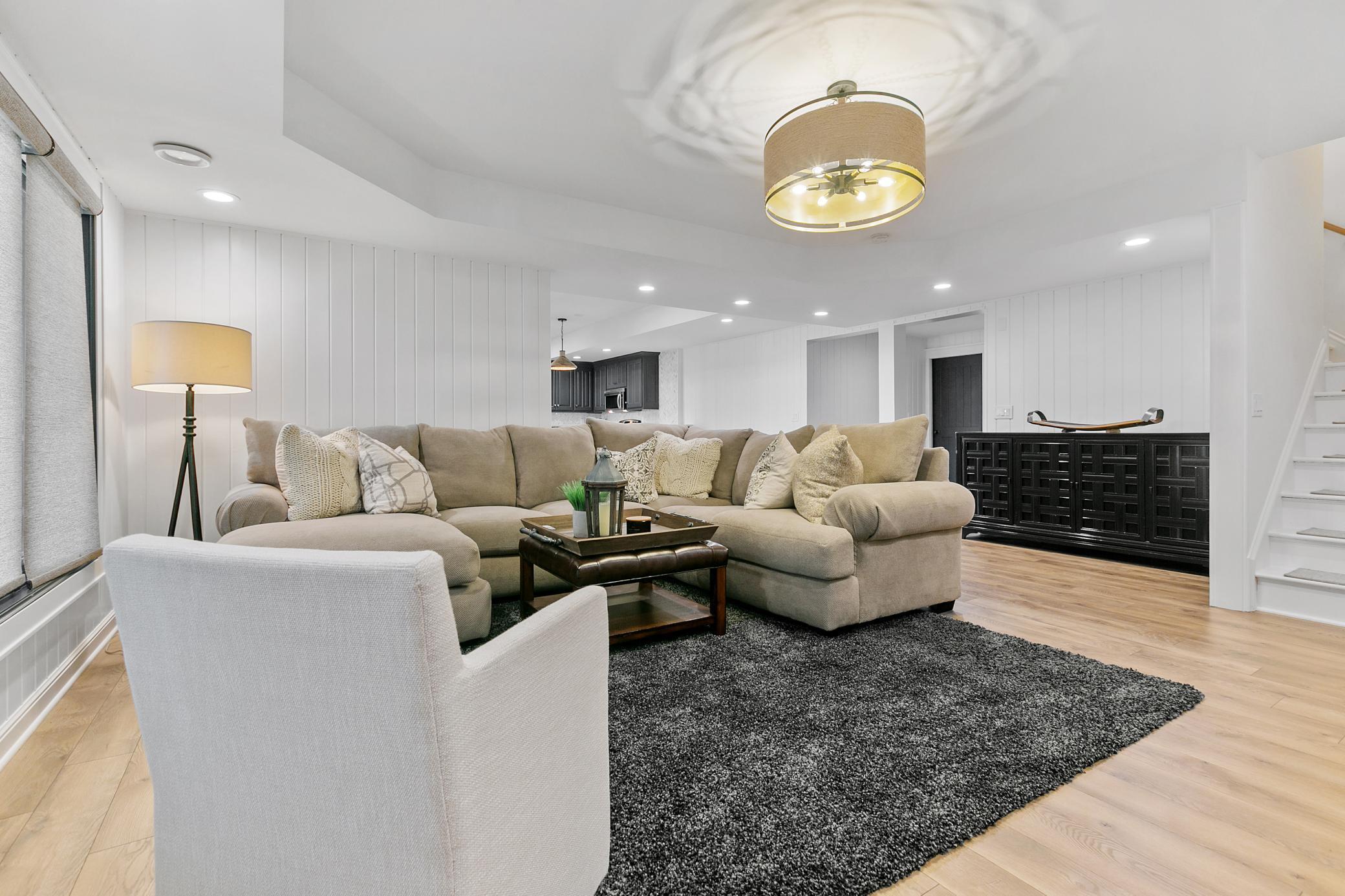 Basement recreation room also has a cozy fireplace, shiplap detail and easy to care for wood floors.