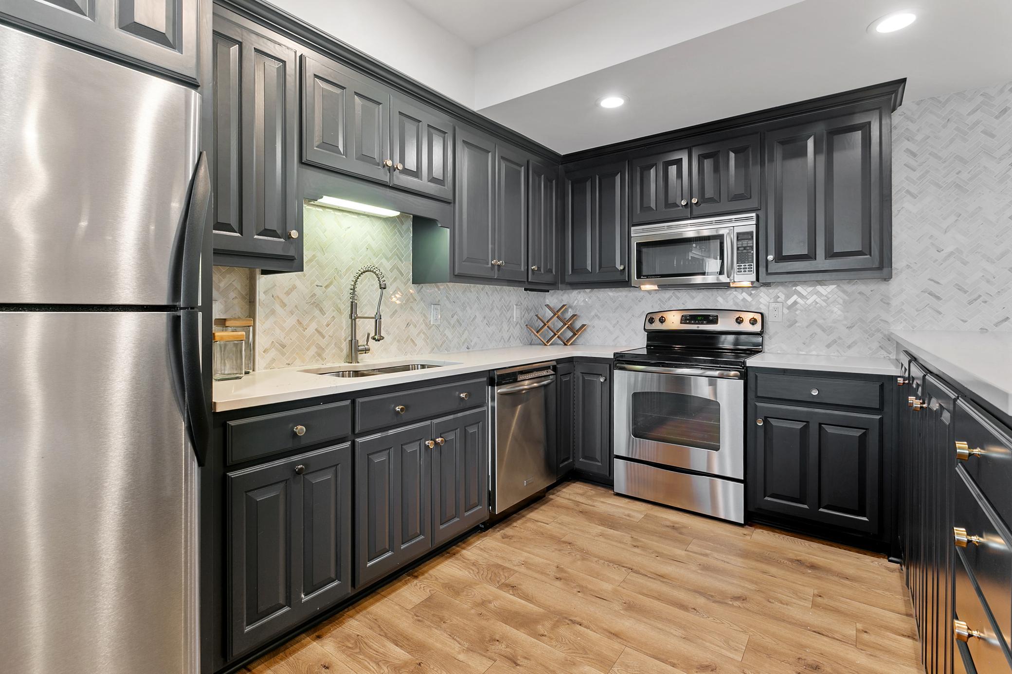 Well-equipped second kitchen with a sink, stove, microwave, refrigerator, ample granite counter space, tile backsplash and plenty of cabinet storage—perfect for summer hosting and entertaining.