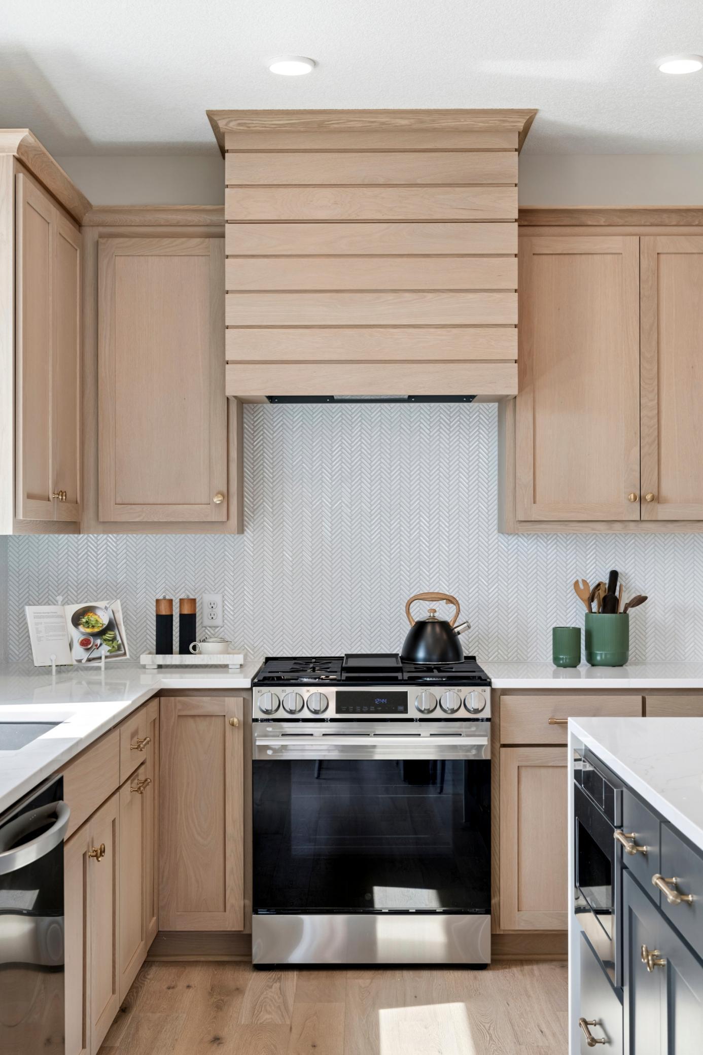 Stylish tiled backsplash paired with a statement plank-style range hood! *Photos are of like home and may not depict actual home plan. Configurations, features, materials and finishes may contain options that are not included in the price.