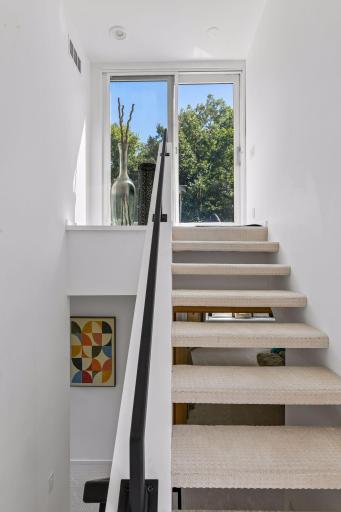 Sunlight fills the staircase as it leads upward to the home’s private roof deck, creating a bright and inviting transition to an elevated outdoor space.