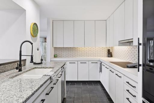 The Kitchen blends contemporary design with elevated finishes, featuring a designer tile backsplash, new countertops with a striking waterfall edge, and a premium appliance package including KitchenAid and Sub-Zero.