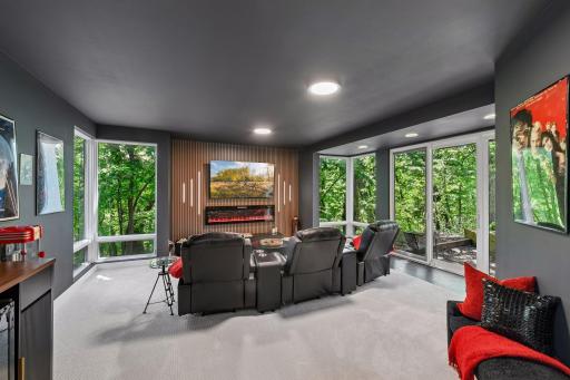 A sophisticated Theatre Room takes center stage in the newly finished lower-level wing, featuring a dramatic slat wall and sleek linear fireplace.