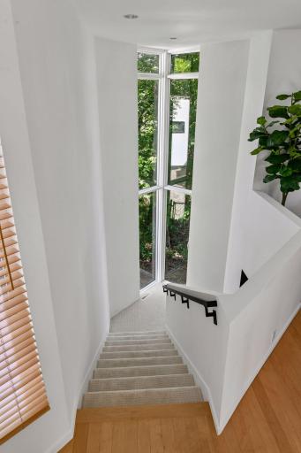 An architecturally distinctive staircase creates a striking transition to one of the lower-level wings, complemented by sleek new railings.