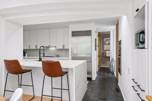 The Kitchen blends contemporary design with elevated finishes, featuring a designer tile backsplash, new countertops with a striking waterfall edge, and a premium appliance package including KitchenAid and Sub-Zero.