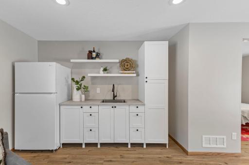 The kitchenette features crisp white cabinetry and a brand-new, never-used refrigerator.