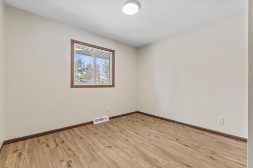 Second main-level bedroom with vinyl plank flooring, neutral colors and tons of natural light.