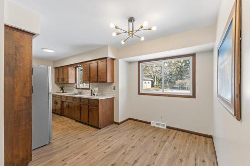 The informal dining area is open to the kitchen and features a large window and updated modern lighting.