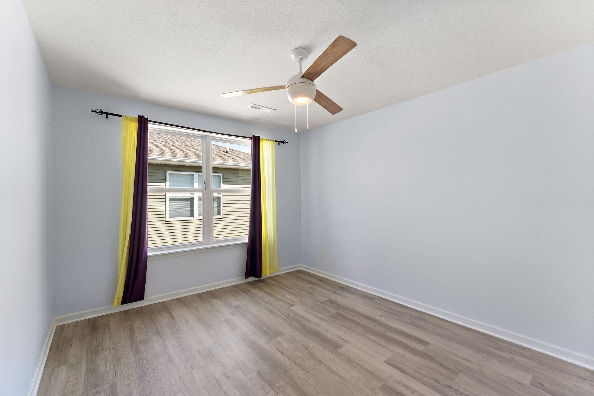 Generously sized second bedroom featuring neutral tones, large windows, and its own dedicated walk-in closet.