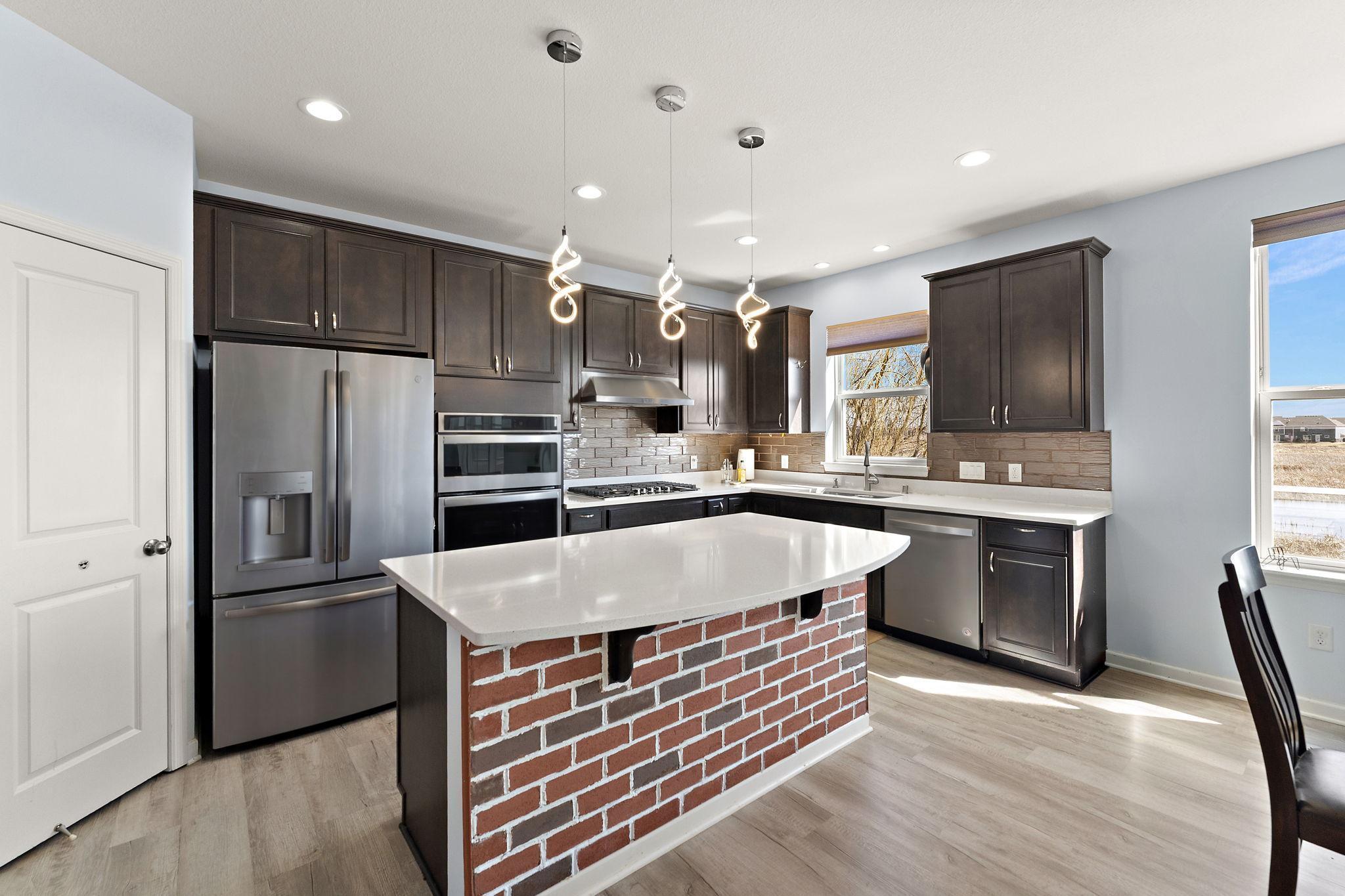 A chef’s delight! The gourmet kitchen features premium dark cabinetry, sleek solid-surface counters, a designer tile backsplash, and high-end stainless steel appliances.