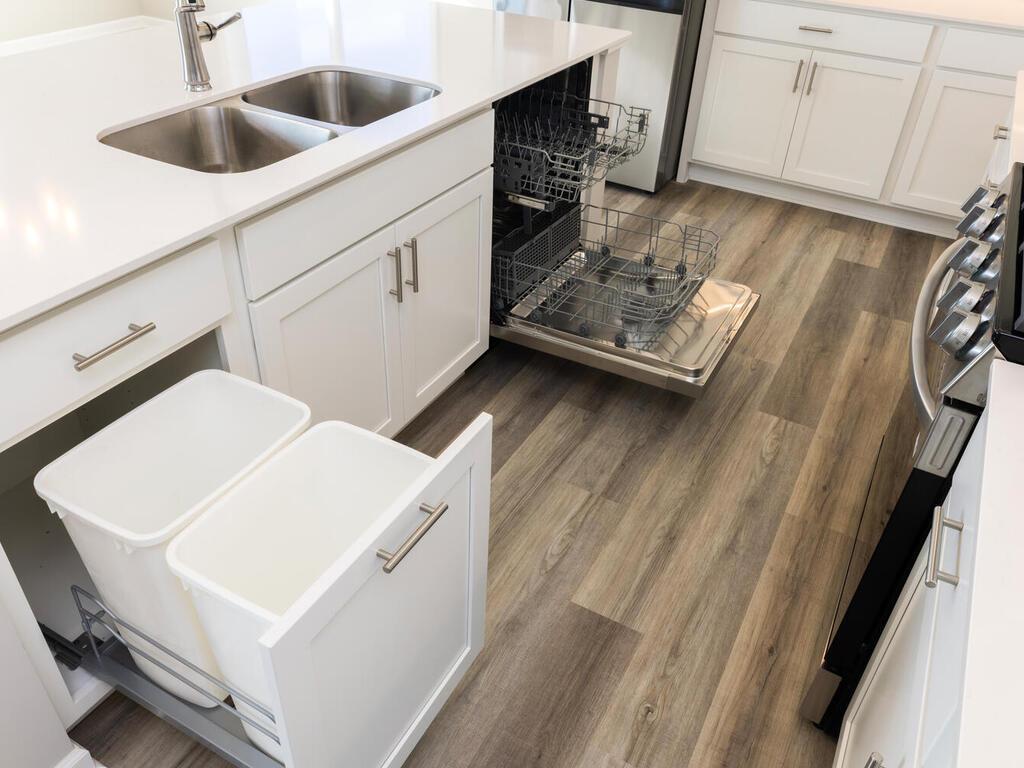PHOTO OF A DIFFERENT HOME WITH SIMILAR PLAN. FINISHES MAY VARY. Kitchen Center Island Features a Trash/Recycling Cabinet Pullout conveniently located next to the sink.