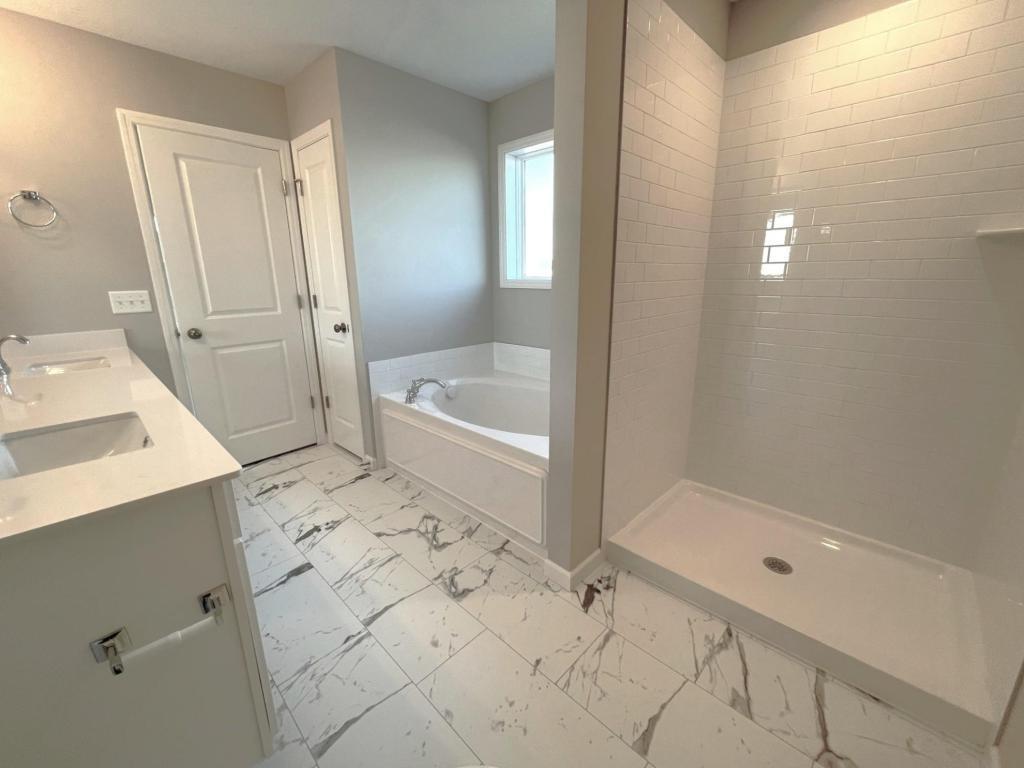 PHOTO OF A DIFFERENT HOME WITH SIMILAR PLAN. FINISHES MAY VARY. Primary Suite Deluxe Bath features a Soaking Tub, Shower with Tile Wall Surround, and Linen Closet.