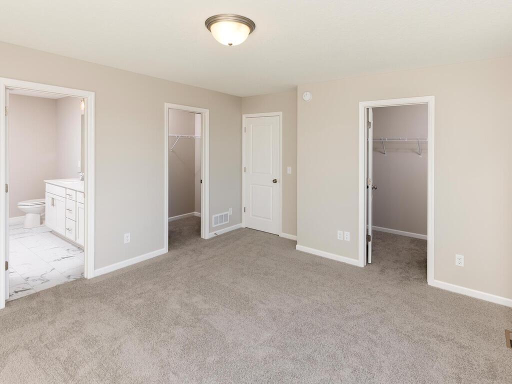 PHOTO OF A DIFFERENT HOME WITH SIMILAR PLAN. FINISHES MAY VARY. Primary Suite features Two Walk-in Closets.