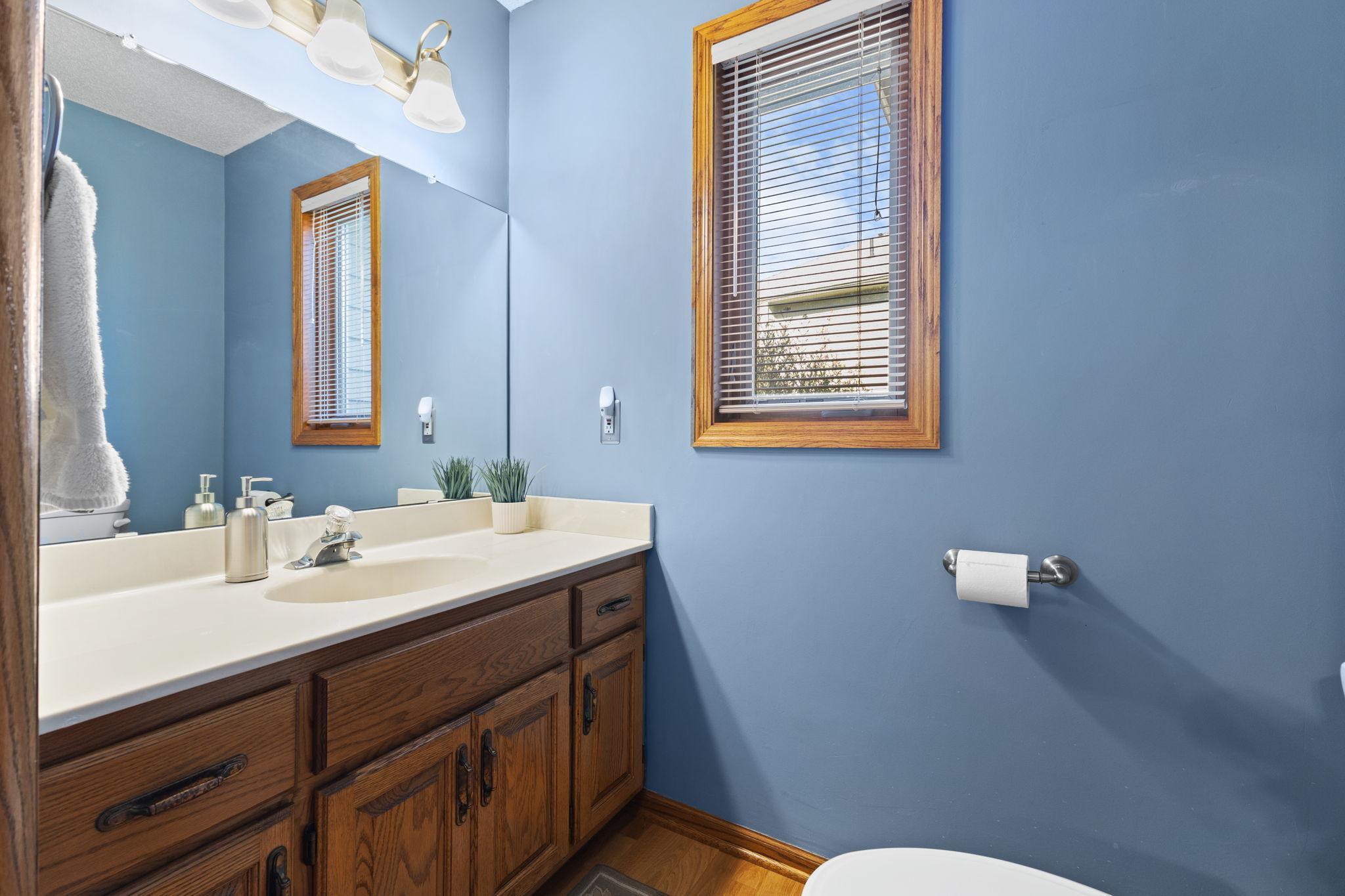 Main level half bath with full vanity for practical storage.