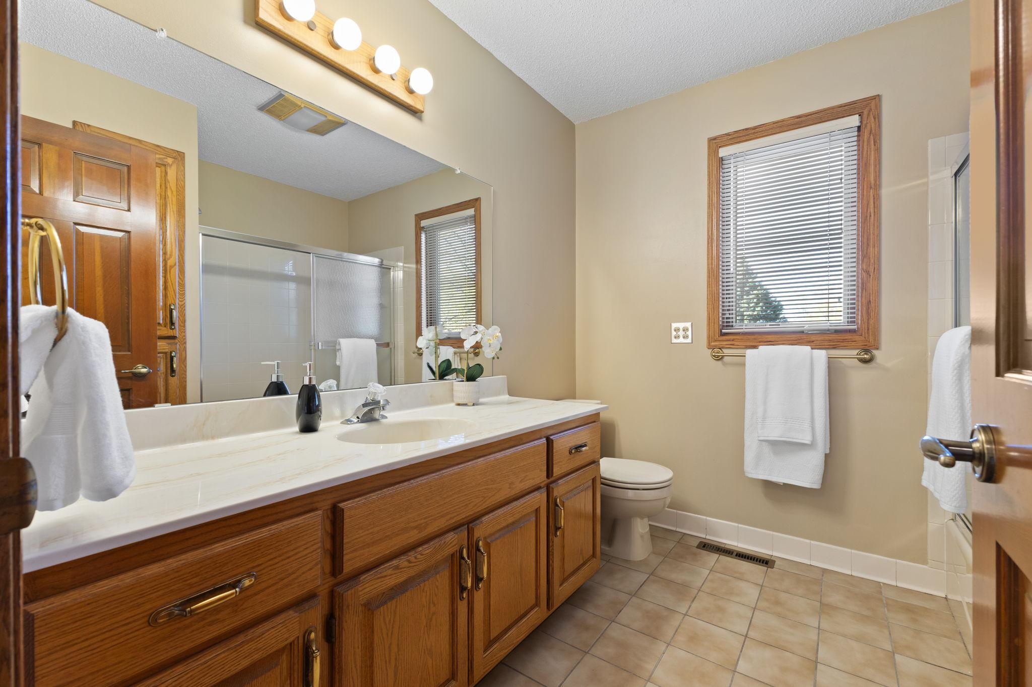 Main bathroom with tile floors plus generous vanity surface & storage space.