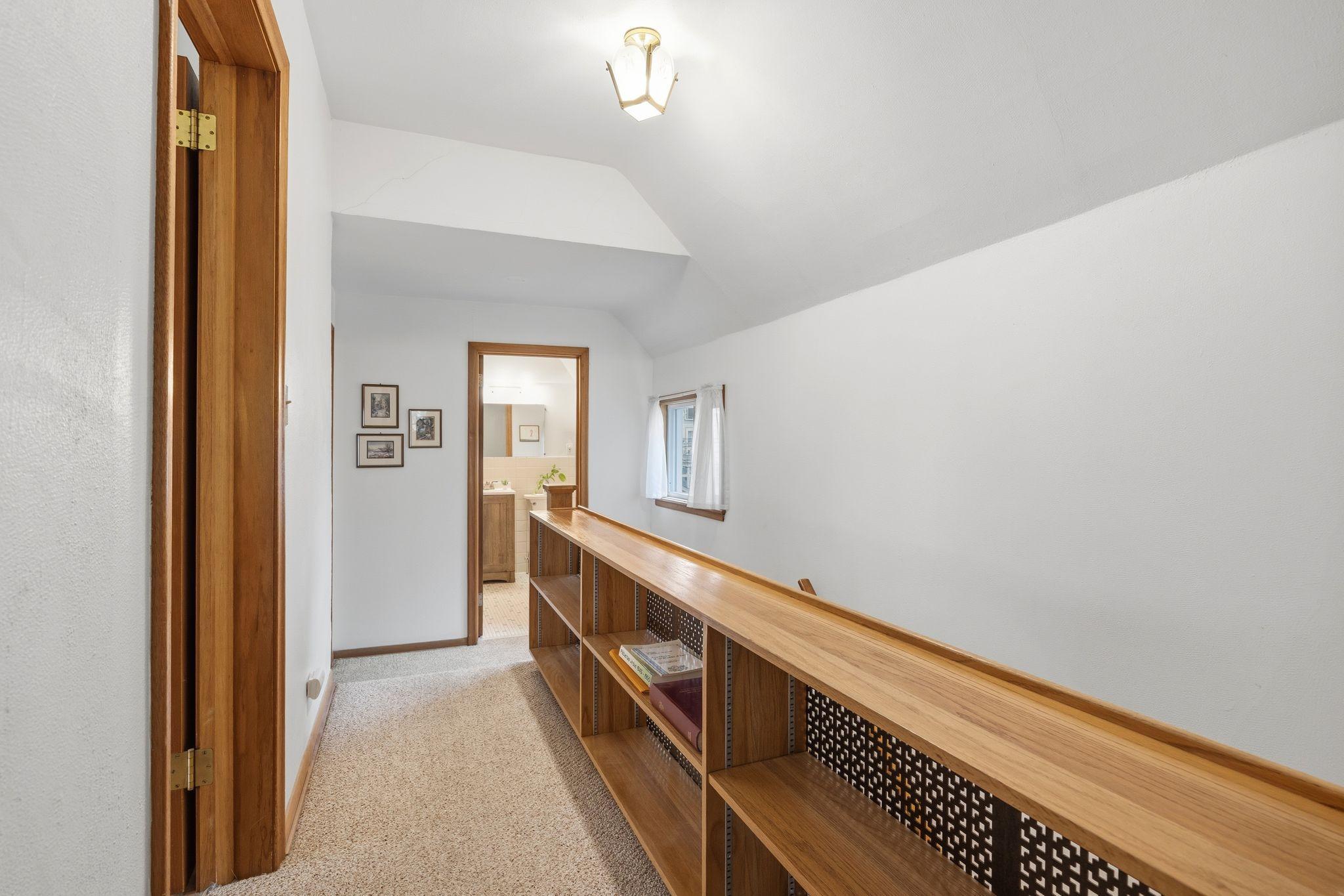 Hallway on the 2nd floor with a built in bookshelf. The full bathroom is through the door straight ahead. There is a door to the attic on the left. There is also a large hall closet to the right that is not captured in this photo.