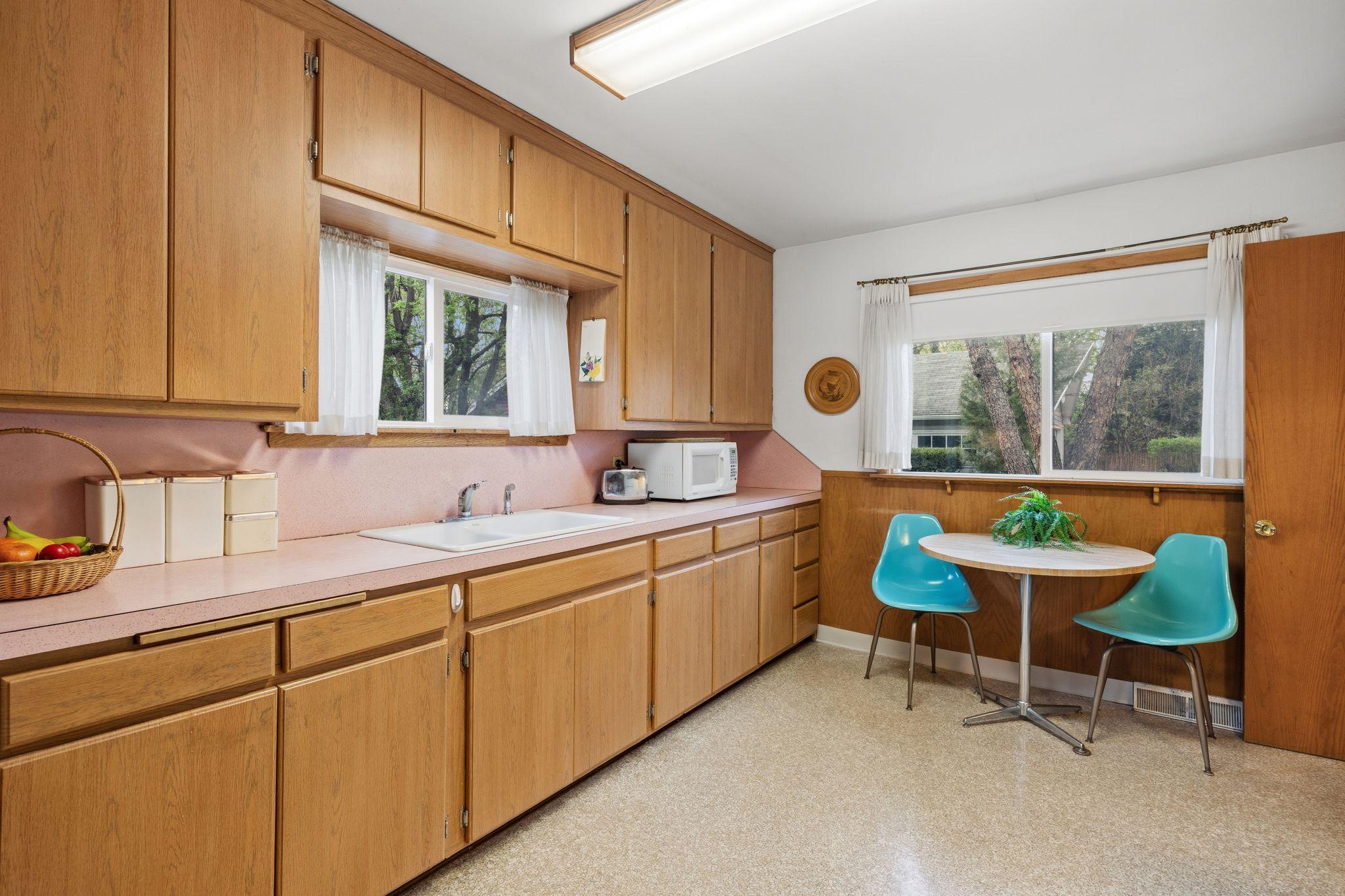The vintage pink countertops offer a playful mid-century aesthetic that complements the home's historic character. Ample counter space and a sensible workflow make this a practical kitchen for daily use.