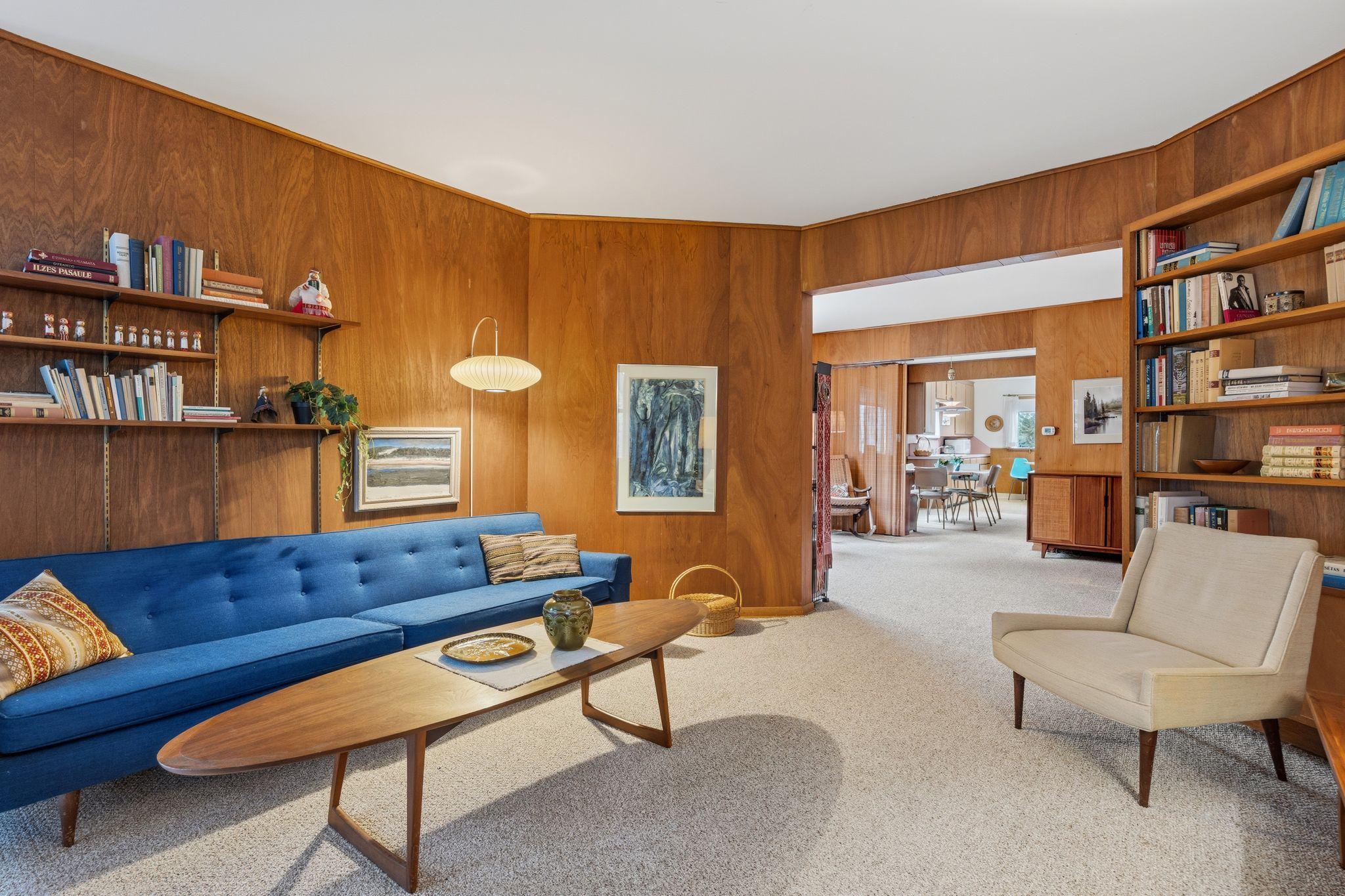 The living room features authentic teak wood-paneled walls that add a warm, mid-century modern texture to the historic 1884 architecture.