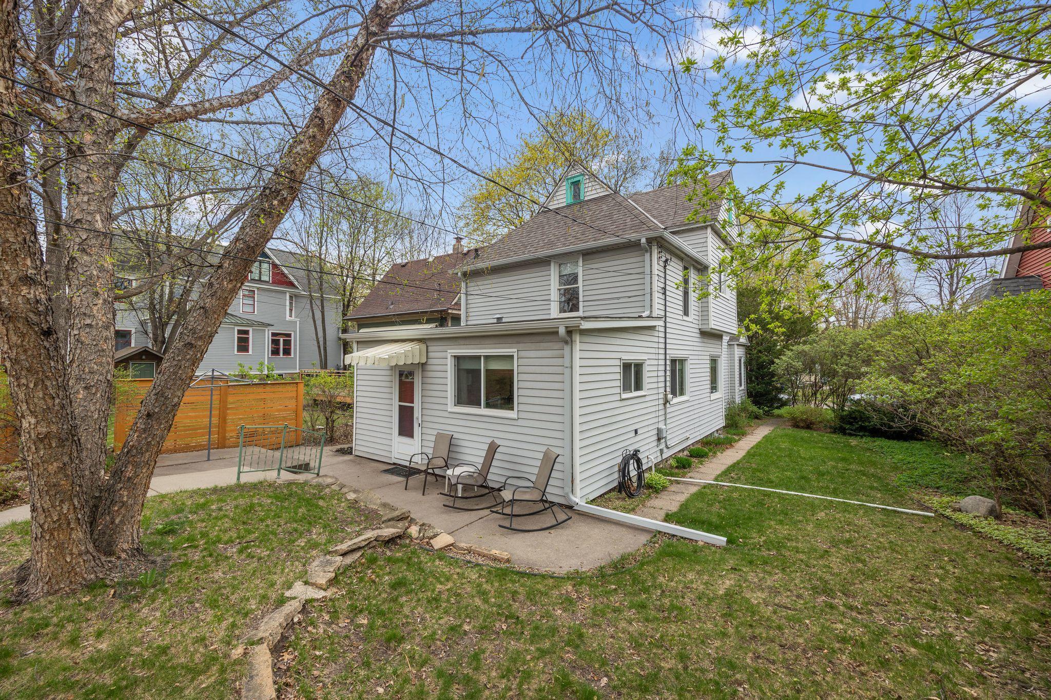 View of the back yard and side yard. There are perennials planted around the yard which include iris, lily of the valley and lilacs.