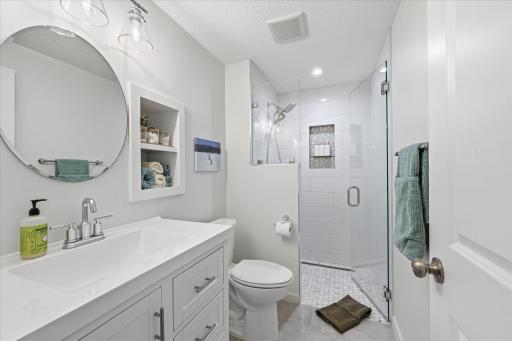 Lower level three quarter bath offers step in tile shower, built in nooks and an elongated sink