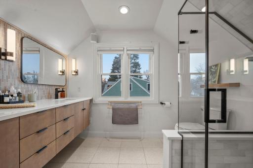 Bright and cheery updated 3/4 primary bathroom with custom glass walk in shower, double sink and in-floor heat~