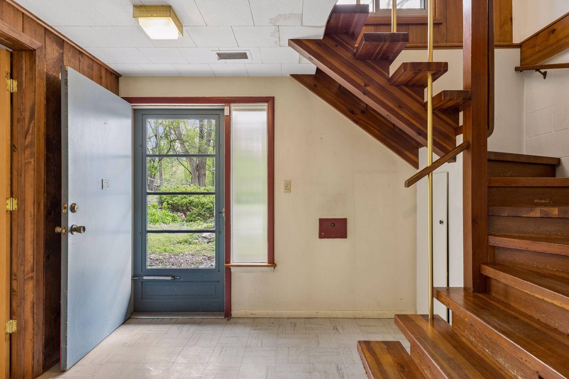 Front entry door with side light. Hardwood treads on MCM vintage gentle turning spiral stair case.
