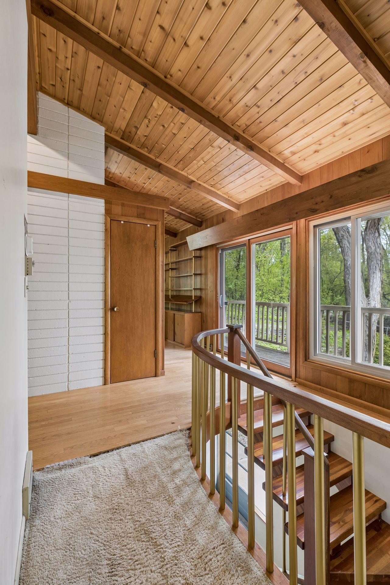 Mid-century modern detail. Hardwood floors in public rooms. Carpeted areas have plywood floors. Doors lead to front deck (in need of replacing).