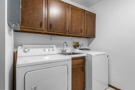 Convenient in-unit laundry room with a sink and added cabinetry for extra storage.