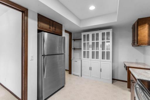 The kitchen offers ample cabinetry space, including a glass-front cabinet. This view also shows access to the in-unit laundry room.