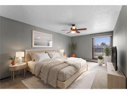 The unit includes two bedrooms, including a primary suite with carpeted floors, a ceiling fan, and a private Â¾ bathroom. (Digitally Staged)