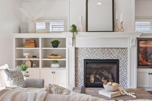 Custom built-ins flank a striking stone tile gas fireplace crowned by a crisp white enamel mantle