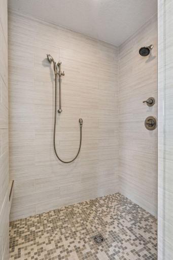 A stunning tiled shower with a gorgeous stone surround offers pure luxury.