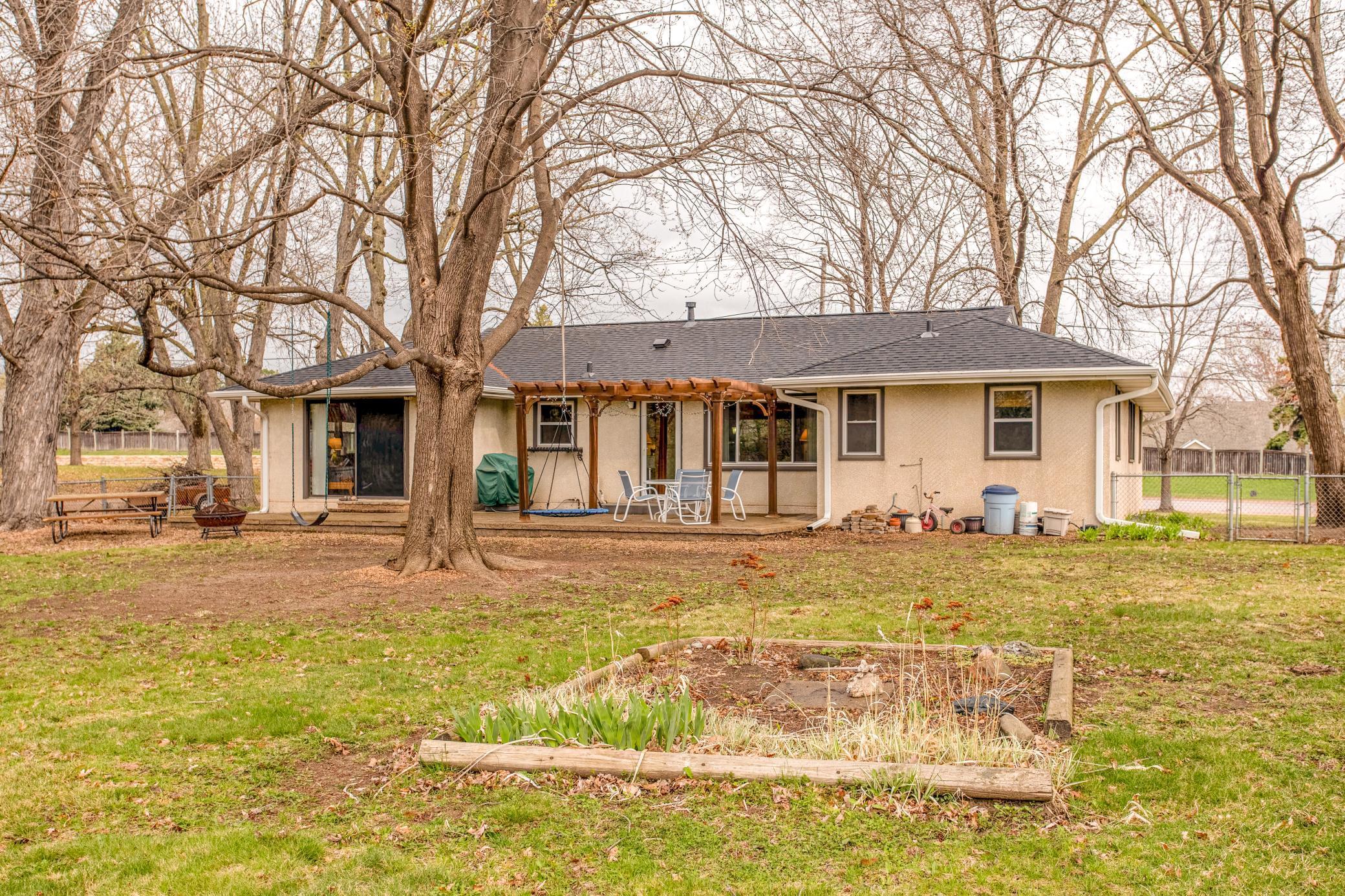 Full rear view of the home highlighting the patio, pergola, and spacious yard—ideal for entertaining and everyday enjoyment.