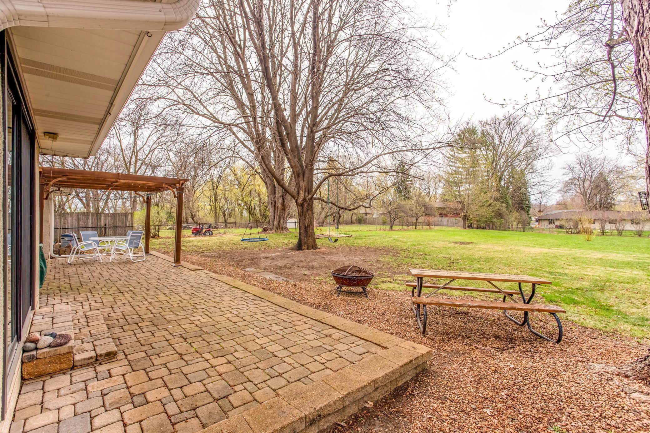 Expansive paver patio overlooking a generous backyard, ideal for gatherings, outdoor dining, and enjoying peaceful surroundings.