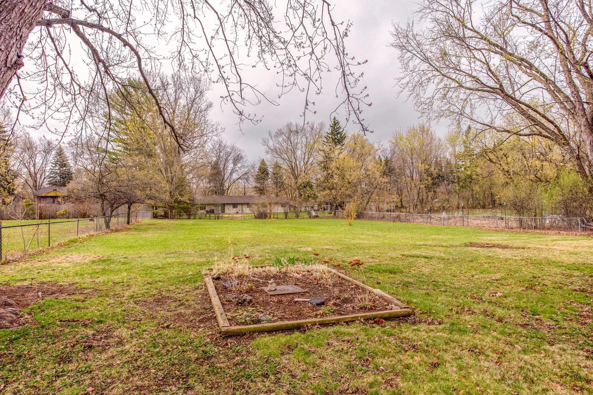 Private backyard view from the patio, showcasing mature trees and ample green space for recreation.
