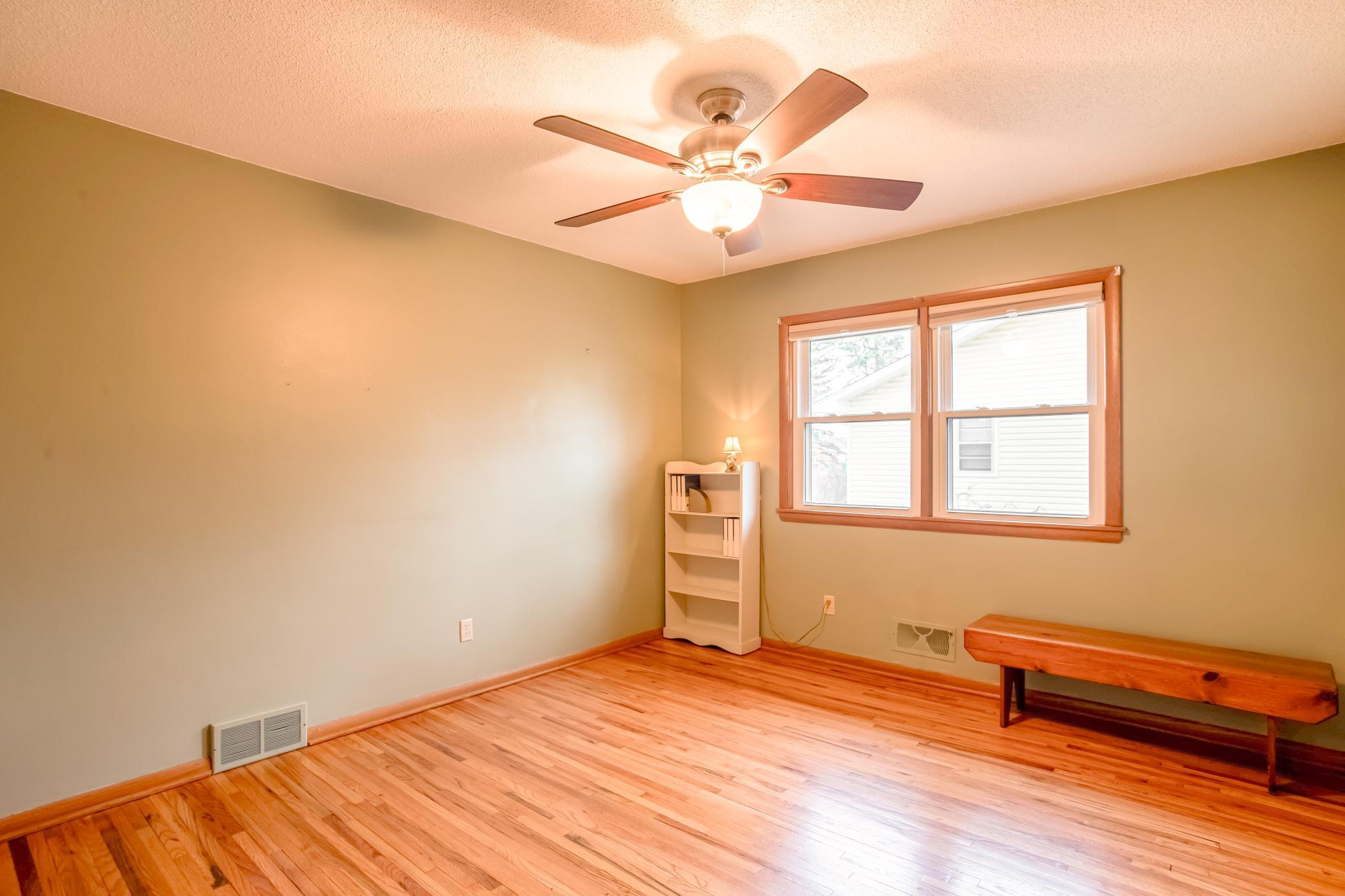 Versatile bedroom with hardwood flooring and neutral tones.