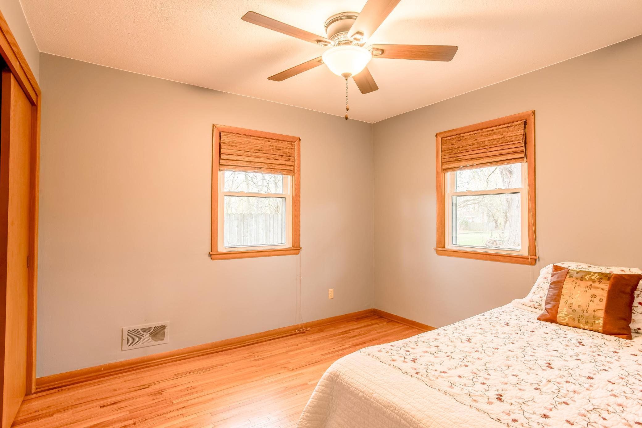 Bright bedroom with hardwood floors and dual windows offering natural light.