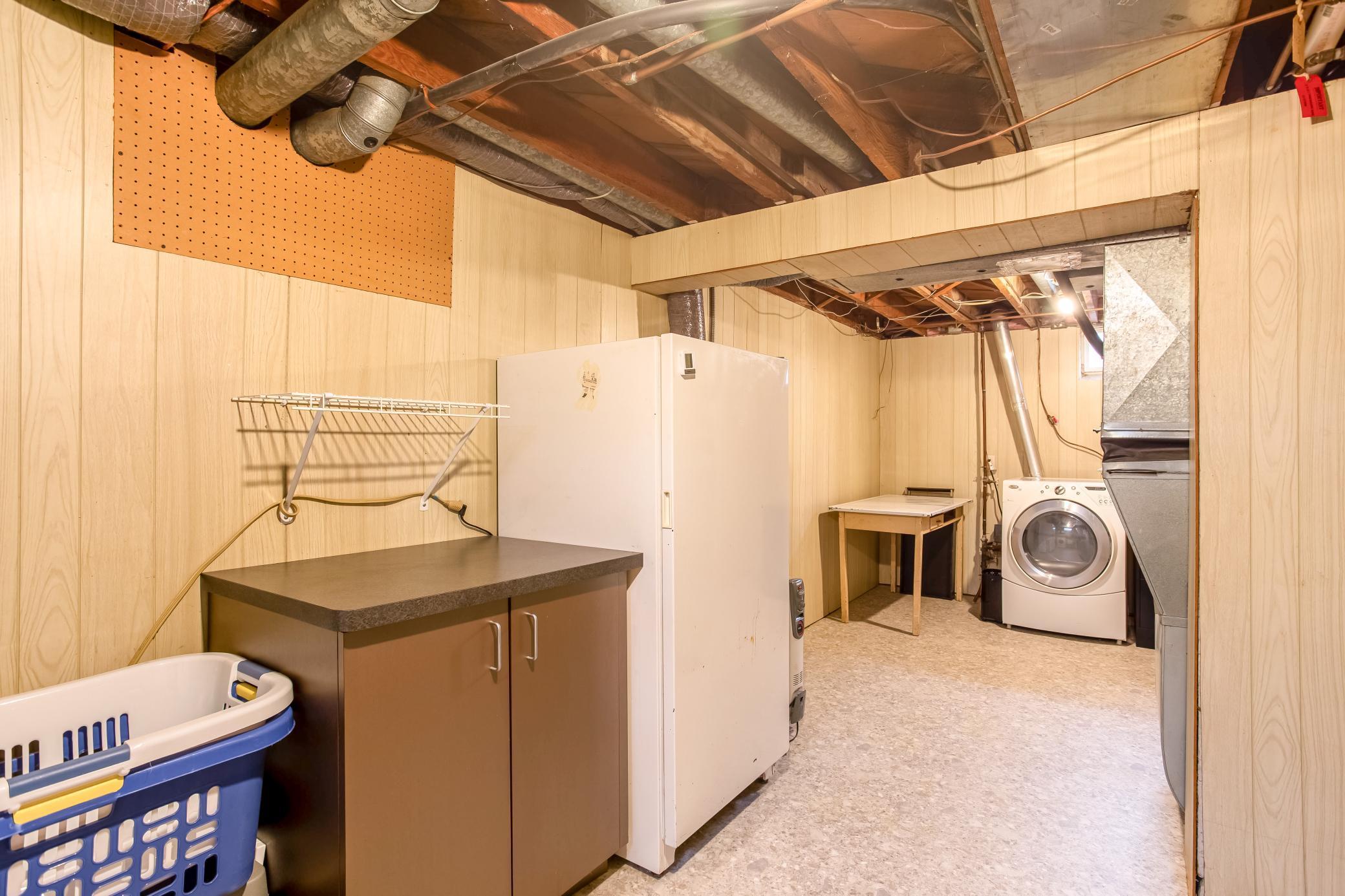 Spacious lower-level laundry area with cabinetry and additional workspace.