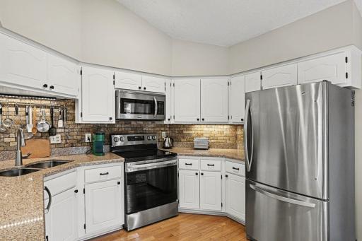 Stone countertops and backsplash with freshly painted cabinets and new hardware